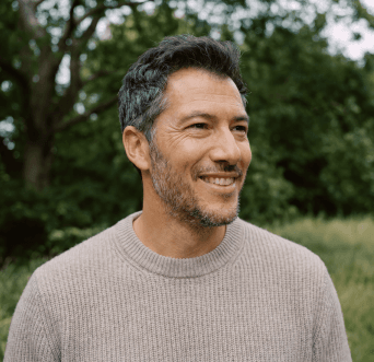 A smiling man with a grey beard outdoors