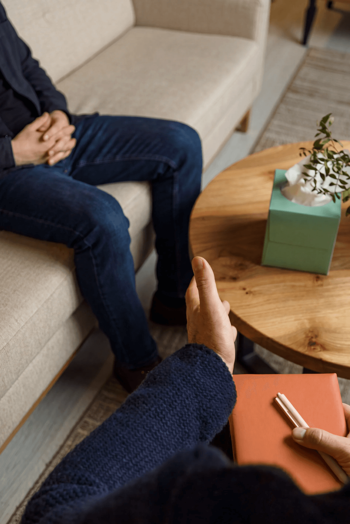 A therapist taking notes across from a client during a counseling session
