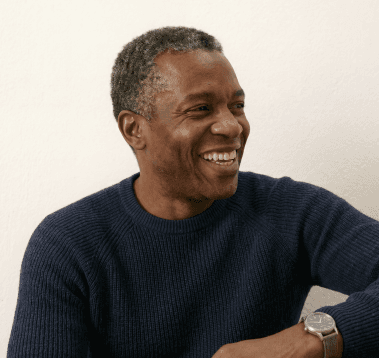 A smiling older man in a navy knit sweater